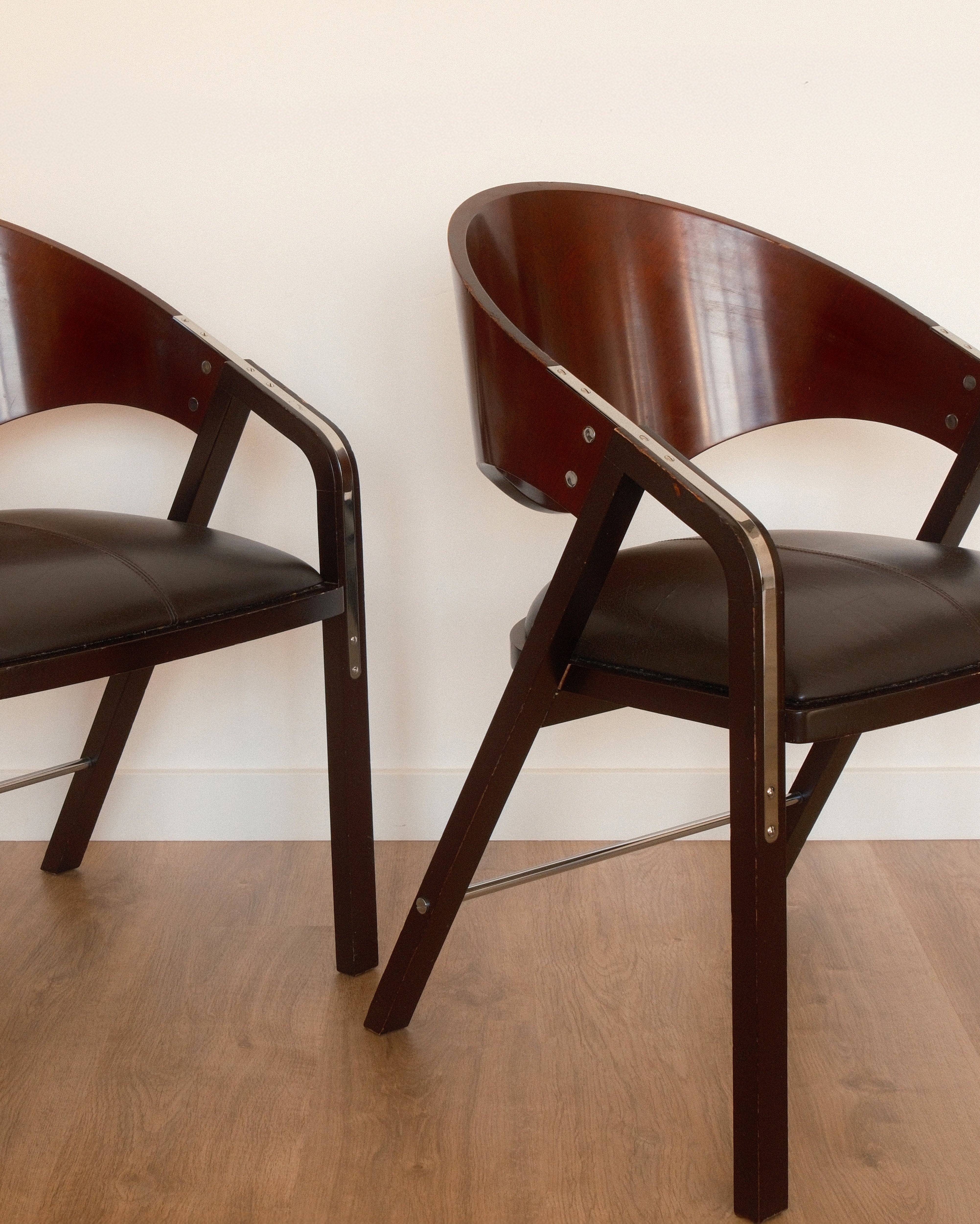 Jaume Tresserra Spinnaker armchairs — close-up of sculptural walnut frame and faux leather seat